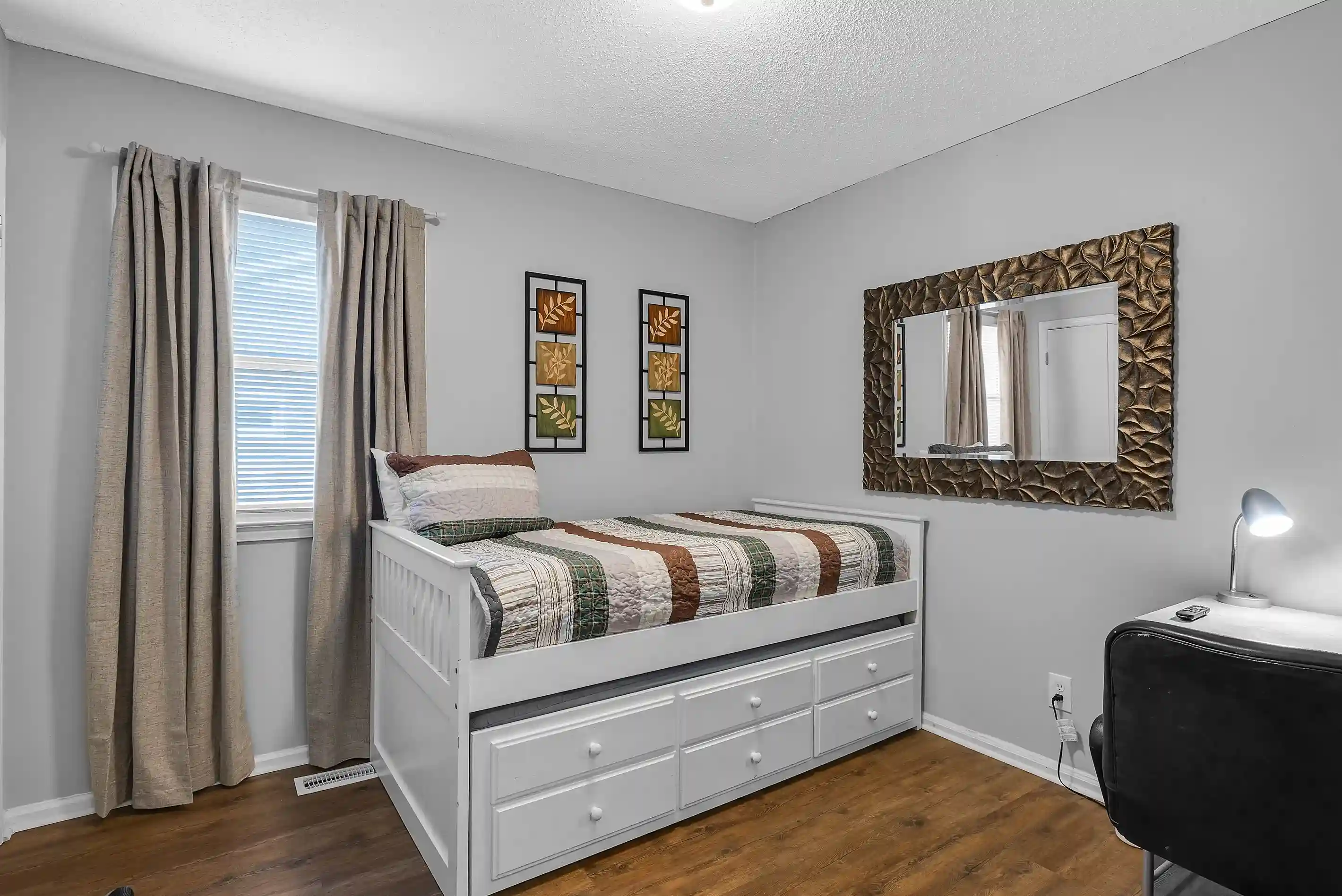 This flexible office/bedroom features a twin bed with a pull-out trundle, a desk for work, and a wall-mounted smart TV for relaxation.