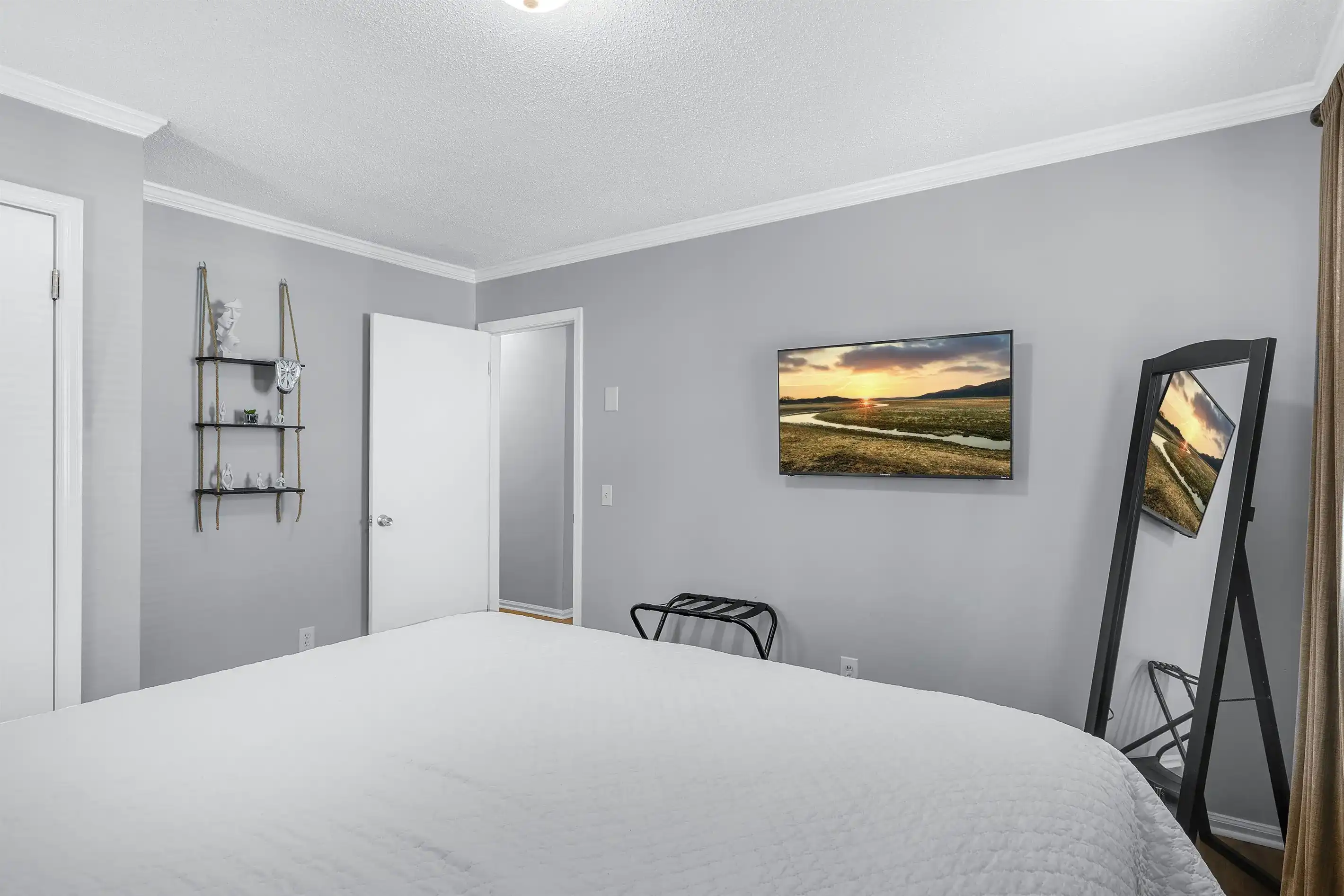 This guest bedroom has a full-length mirror, luggage rack walll-mounted smart TV and a closet with shelving for your belongings.