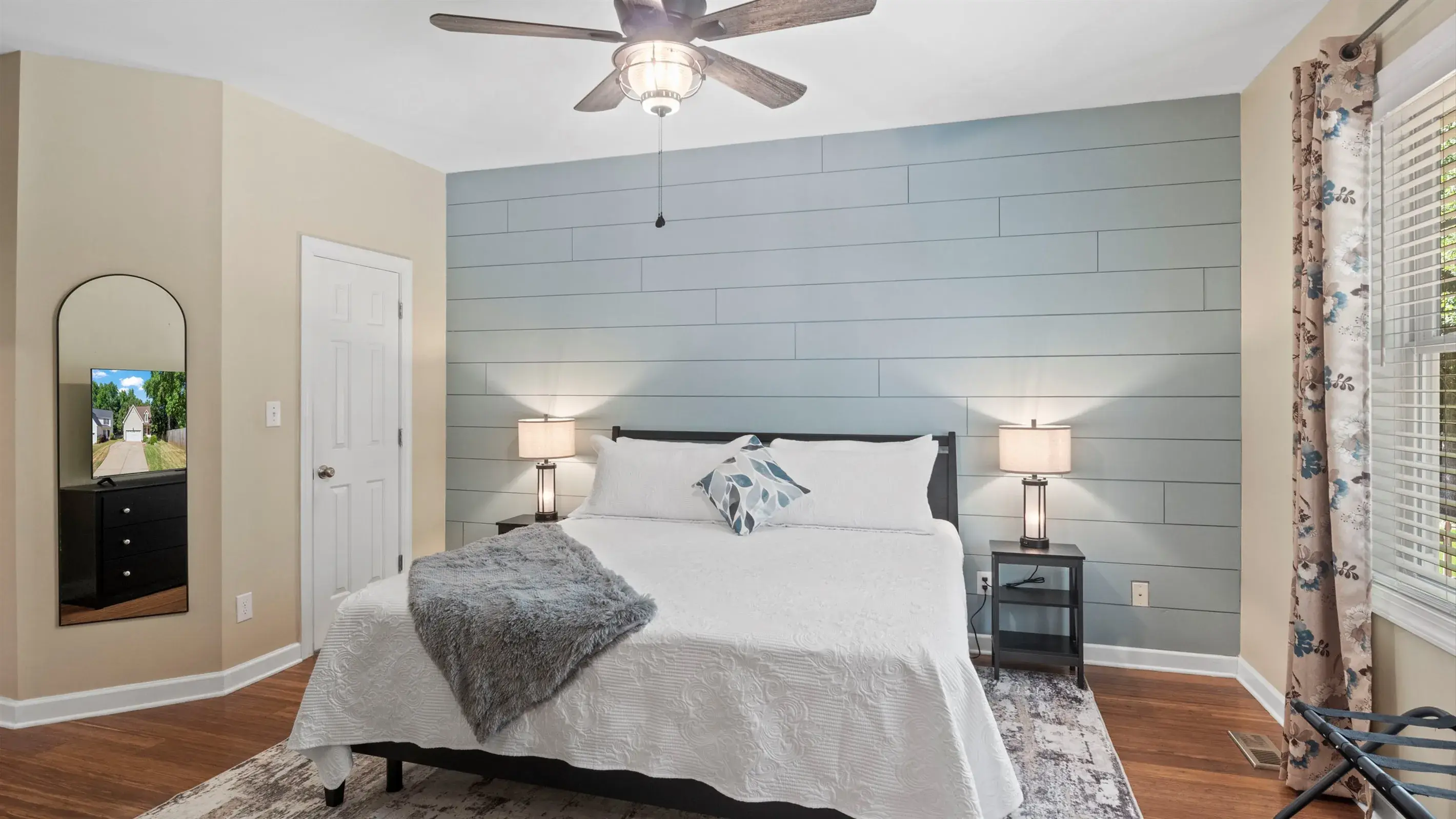The room is complete with nightstands with lamps, walk-in closet, en suite bathroom, full length mirror, luggage rack, dresser and a 55" TV.