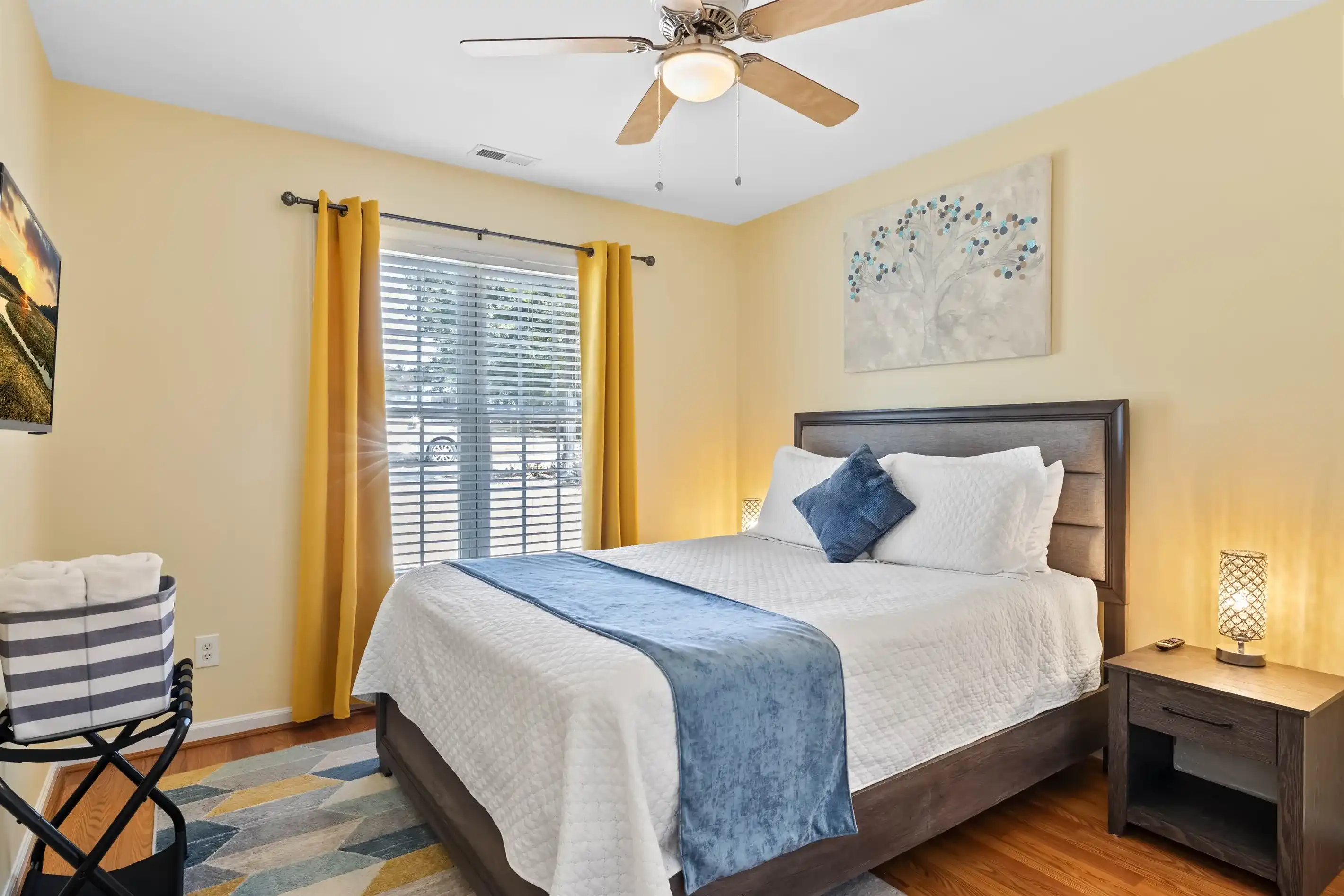 Capturing the essence of comfort, this guest bedroom boasts a queen bed accompanied by a wall-mounted smart TV. A convenient luggage rack is provided.